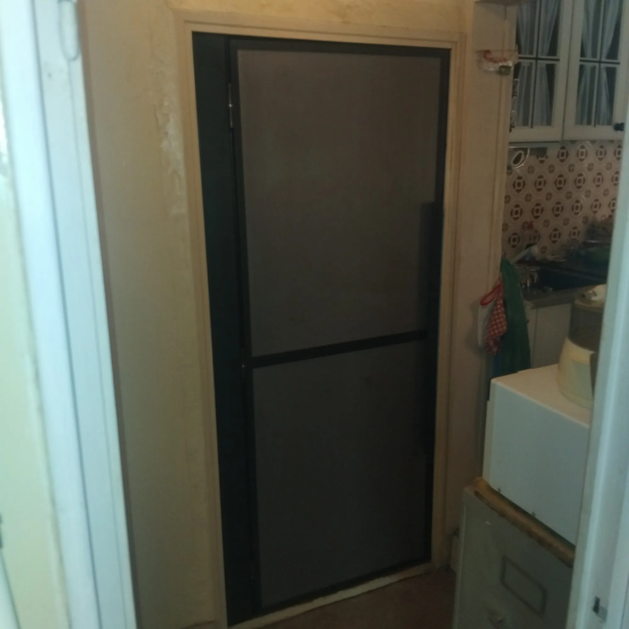 Porte à cadre acier et toile fine posée sur une entrée de service